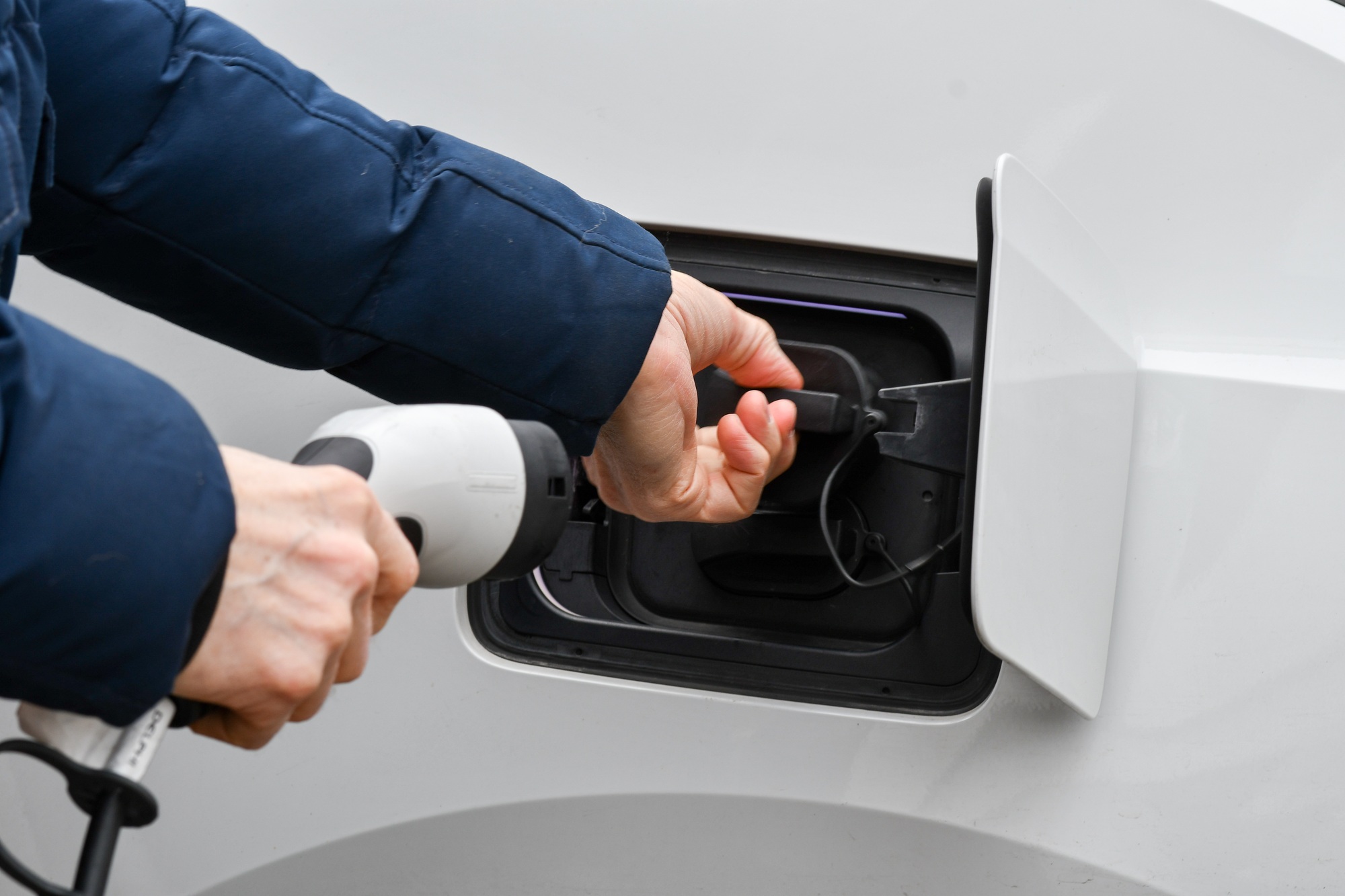 A man putting in charger cable in electric car