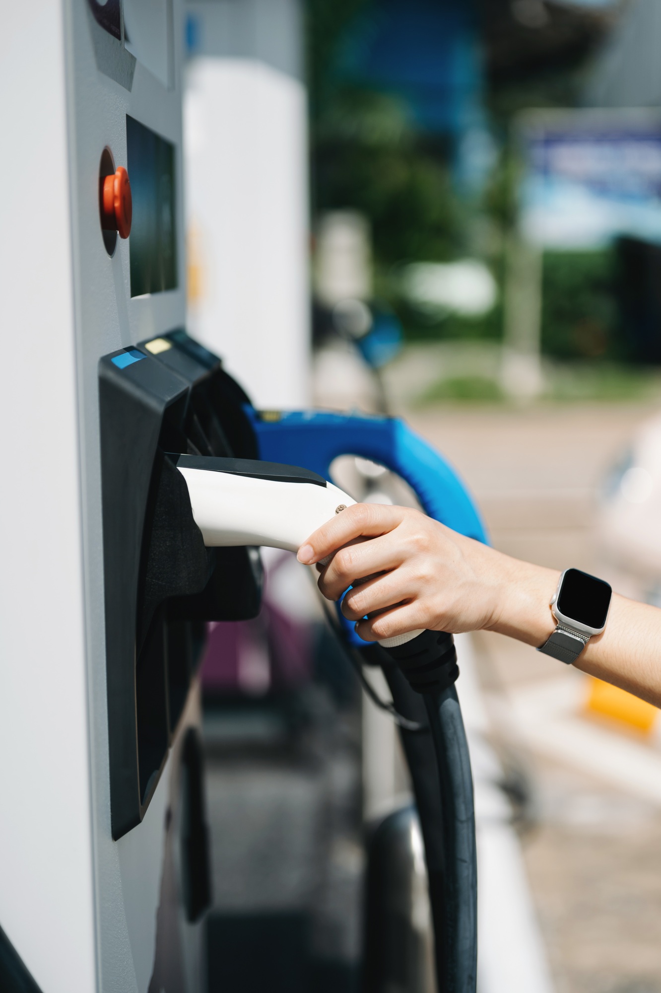 Hand plugging in a charger in an electric car socket.Electric car or ev is charging at station